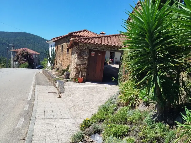 Fachada da casa de pedra, com porta de madeira e telhado de telha