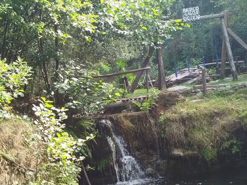 Pequena queda de água a cair numa lagoa, rodeada de vegetação
