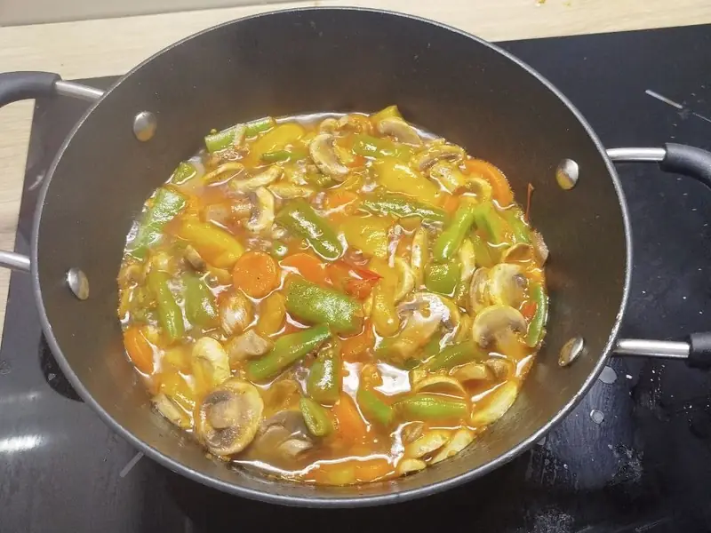 Tacho com cogumelos, feijão-verde e pimento num molho avermelhado